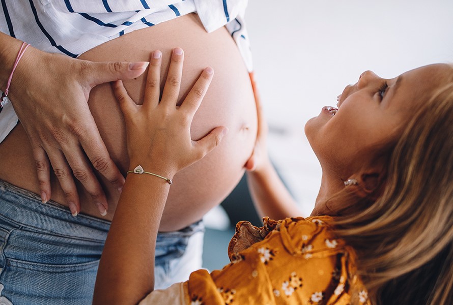 Berührende Familienmomente Ein kleines Mädchen legt die Hände auf den Babybauch seiner Mutter – ein liebevoller Moment voller Vorfreude.