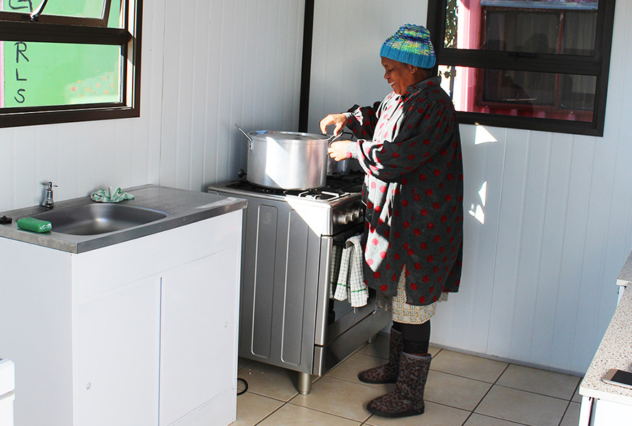 Gladys am Herd – mit Herz und Engagement In der neuen Küche bereitet Gladys mit viel Liebe eine warme Mahlzeit für die Kinder zu – ein sichtbares Zeichen des Fortschritts in Nkululeko.