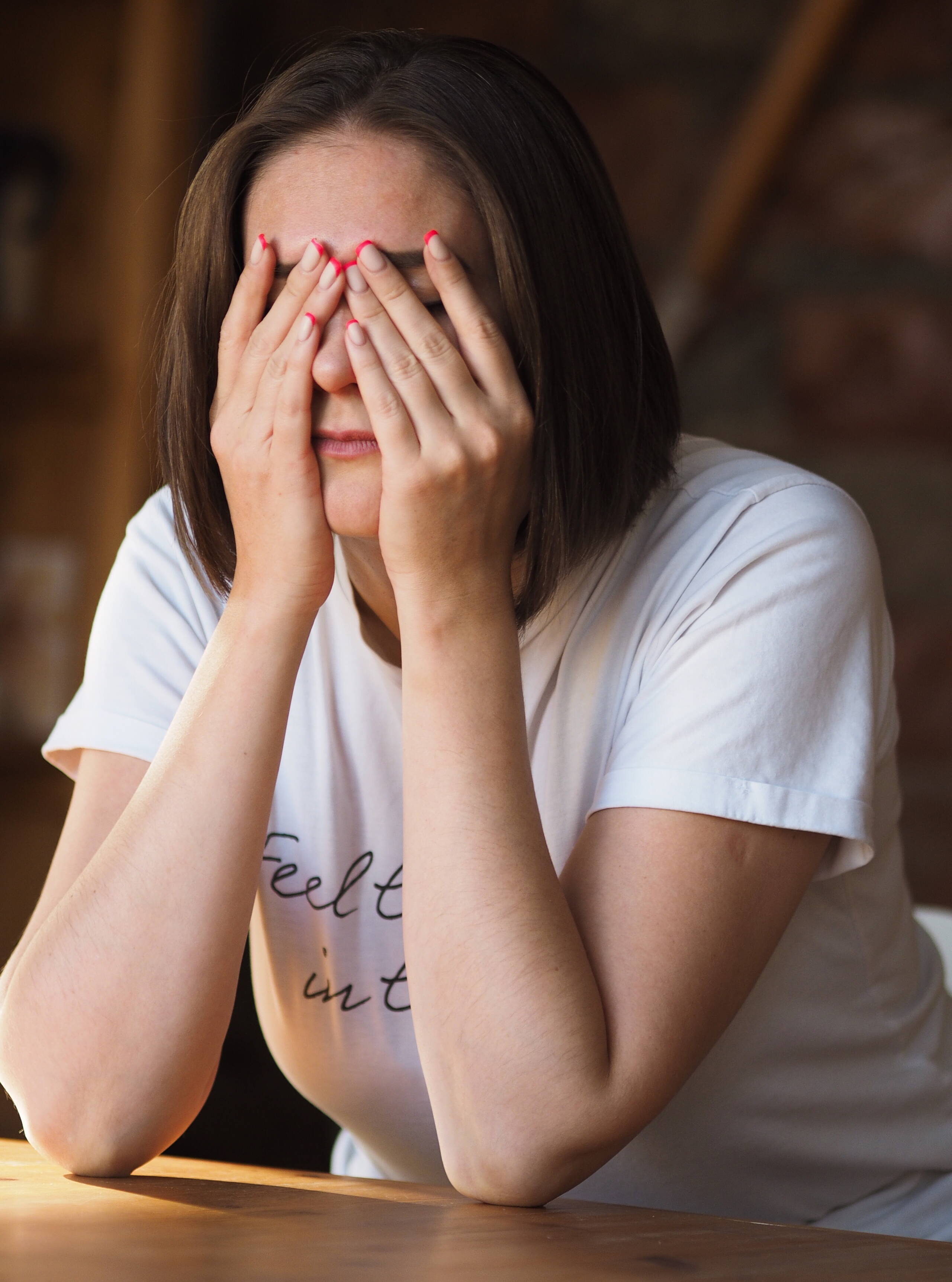 In der Not – Hilfe, die ankommt Das Bild zeigt eine Person mit gesenktem Kopf, die am Tisch sitzt. Es symbolisiert eine belastende Lebenssituation und den dringenden Bedarf an Unterstützung dort, wo die Not am grössten ist.