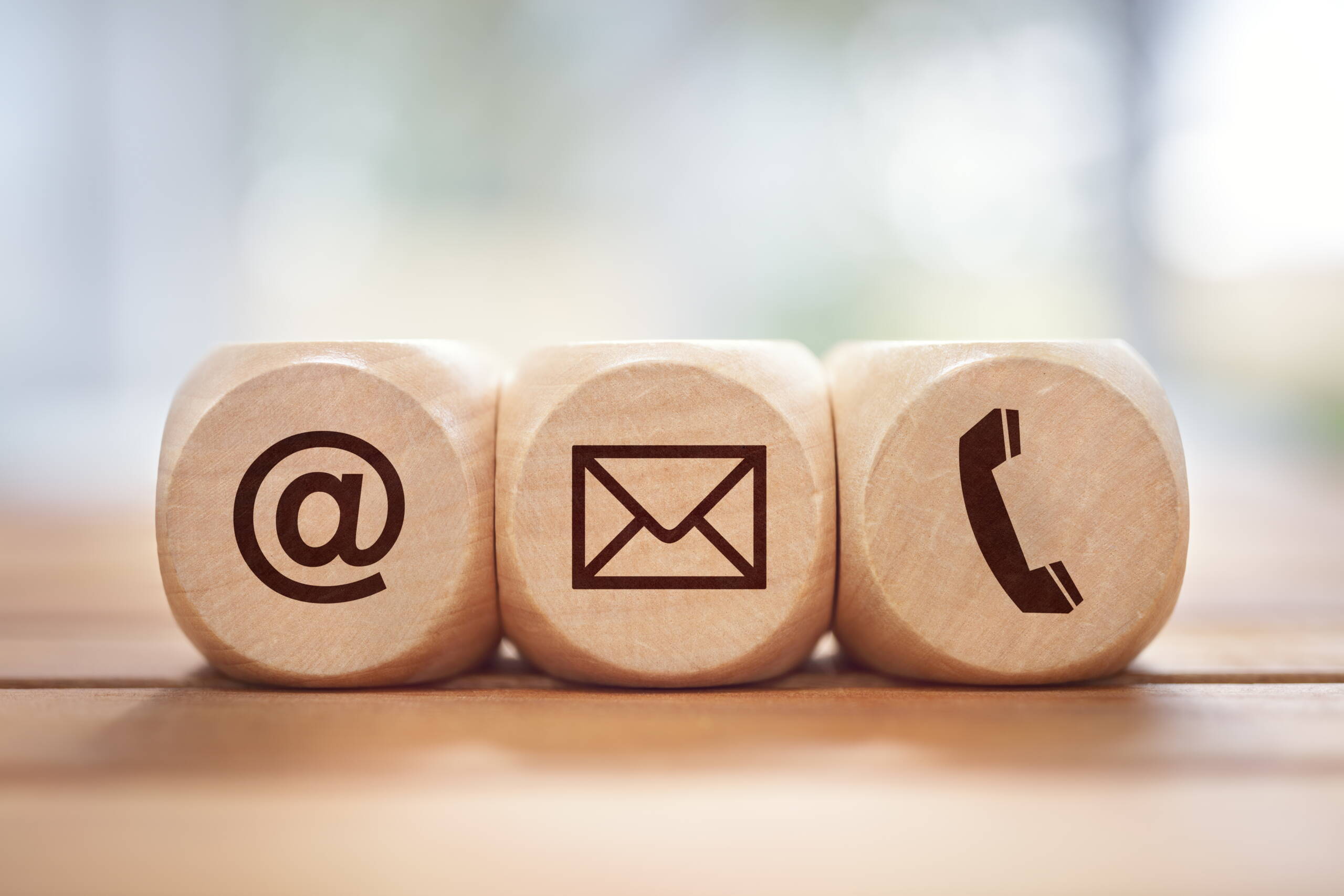 Kontakt auf einen Blick Drei Holzwürfel mit den Symbolen für E-Mail, Post und Telefon stehen für einfache Erreichbarkeit und persönlichen Service.
