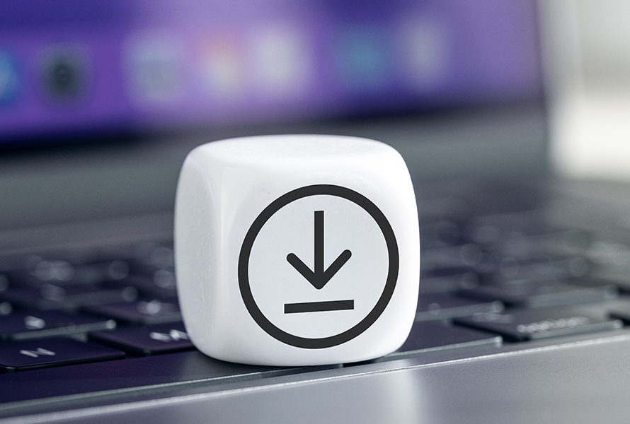 Download-Symbol auf Laptop-Tastatur Das Bild zeigt einen weißen Würfel mit einem schwarzen Download-Symbol darauf, der auf einer Laptop-Tastatur platziert ist. Im Hintergrund ist ein unscharfer Bildschirm mit violetter Farbgebung zu sehen. Der Würfel symbolisiert den Bereich Downloads und hebt die Bedeutung des Herunterladens von Dateien in einer digitalen Umgebung hervor.