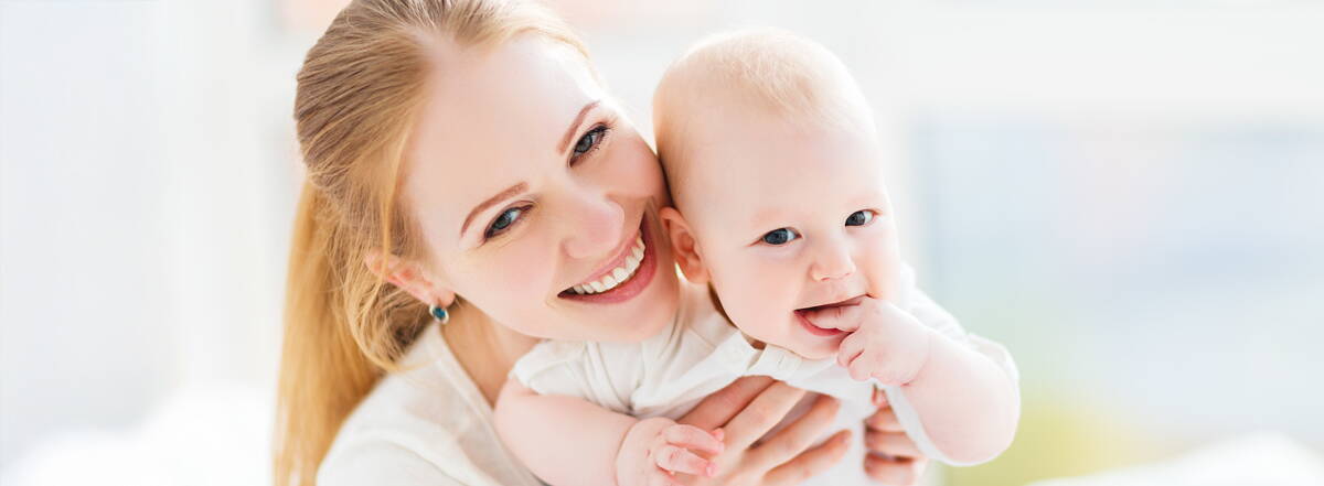 Familienfreundlich versichert Eine Mutter hält ihr Kleinkind liebevoll im Arm. Beide lachen – ein Moment, der zeigt, wie wichtig Sicherheit für die ganze Familie ist.