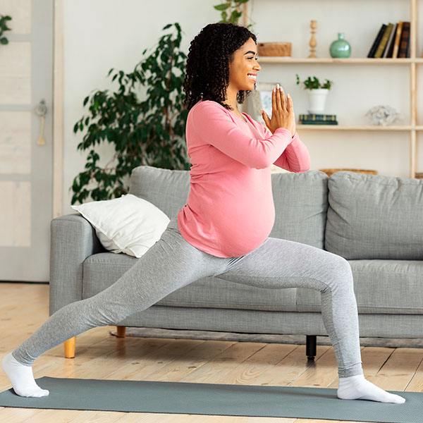 Exercices contre le mal de dos pendant la grossesse Une femme enceinte effectue des exercices d’étirement sur un tapis dans son salon. Une activité physique ciblée peut soulager le mal de dos pendant la grossesse et renforcer la musculature.