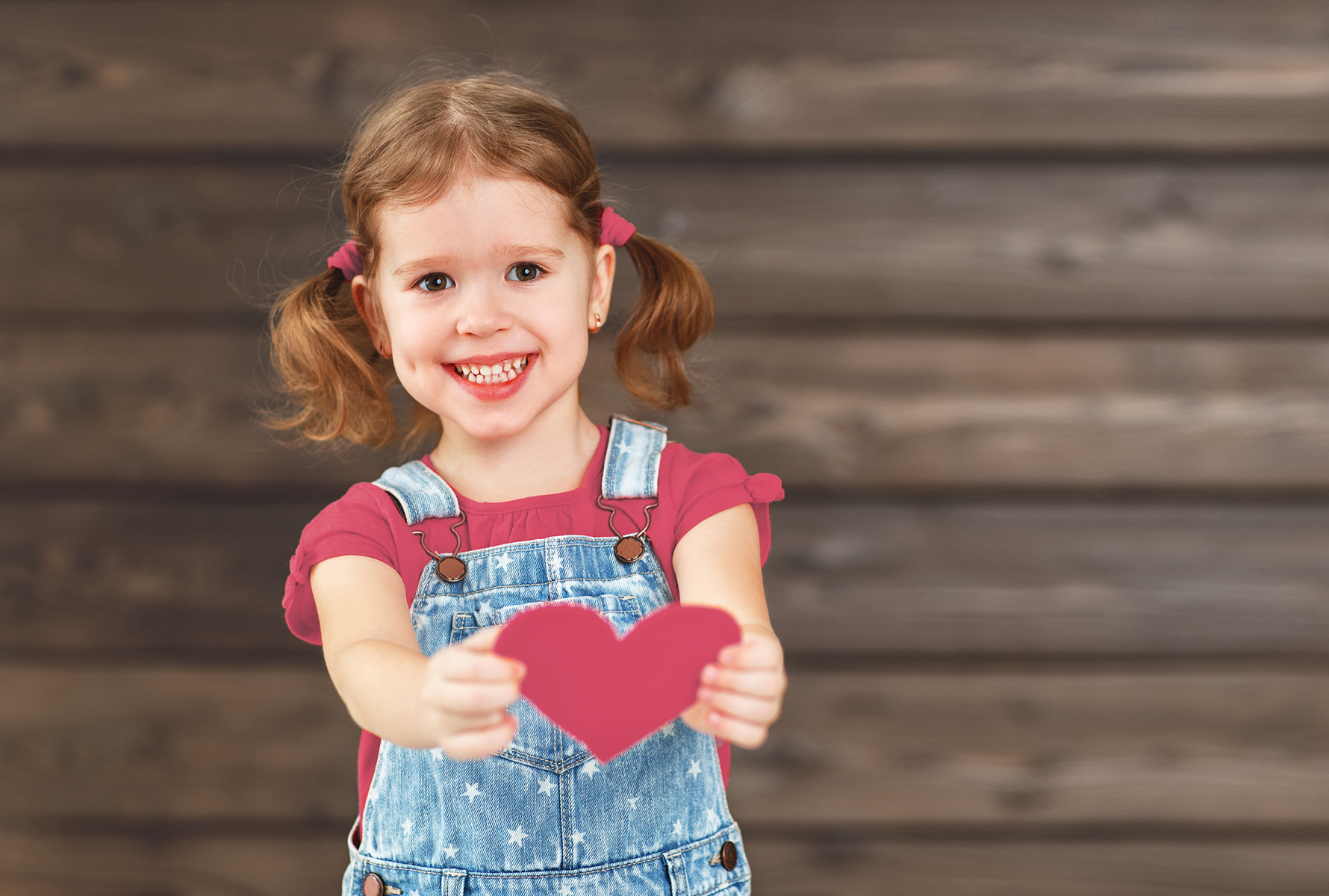 Bambina con un cuore Una bambina porge un cuore verso la fotocamera – un simbolo forte di amore, cura e umanità.