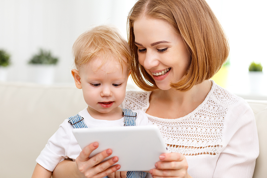Junge Frau mit Kind und Tablet Eine junge Frau zeigt einem kleinen Jungen ein Tablet – ein Zeichen für Unterstützung, Bildung und digitale Nähe.