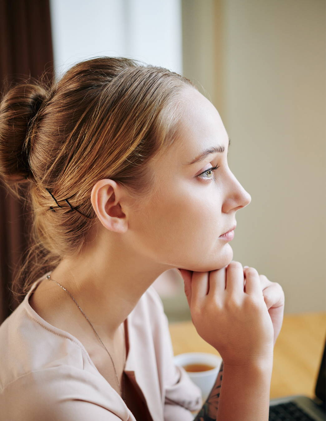 Blonde junge Frau starrt ins Leere Eine junge Frau im Profil stützt ihr Kinn mit den Händen und blickt gedankenverloren ins Leere – ein Moment der typischen Schwangerschaftsdemenz.